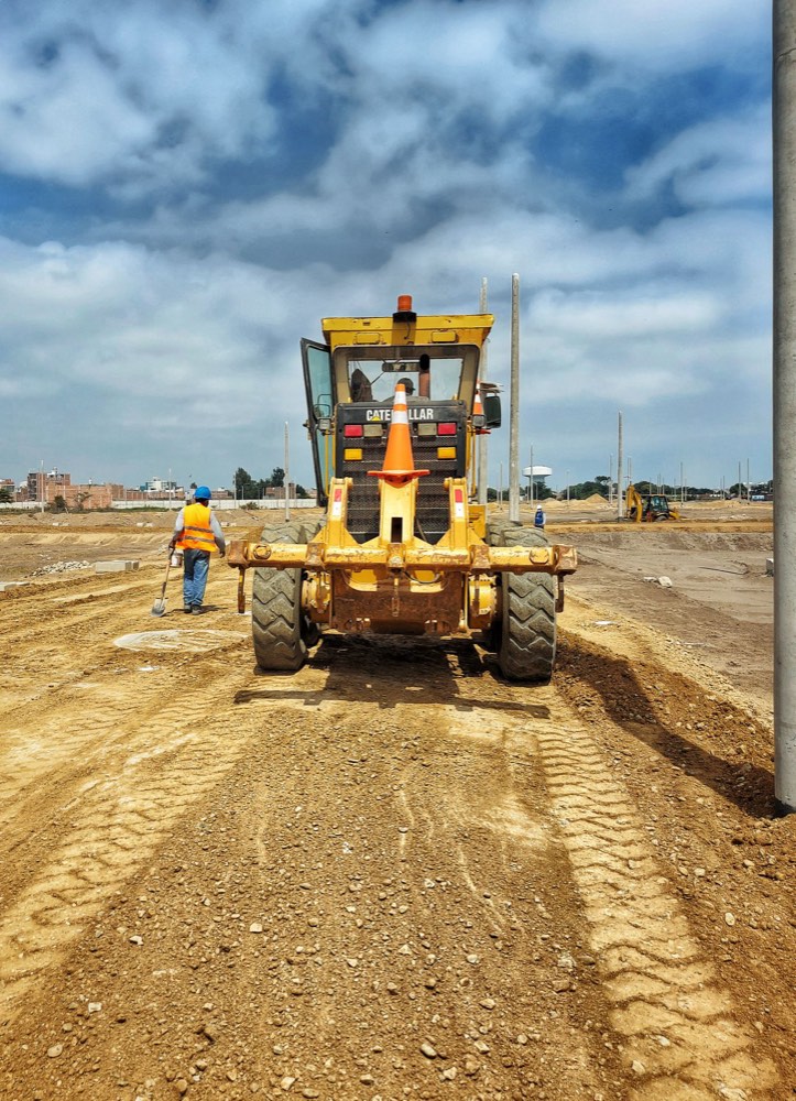 A motor grader levelling a dirt road on a groundworks site