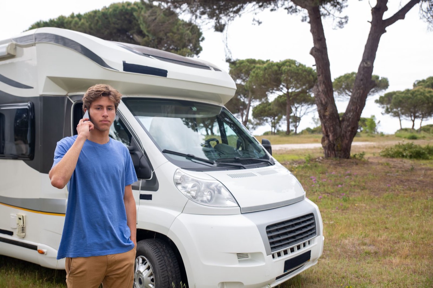 A guest standing beside his motorhome, phoning the park about a site